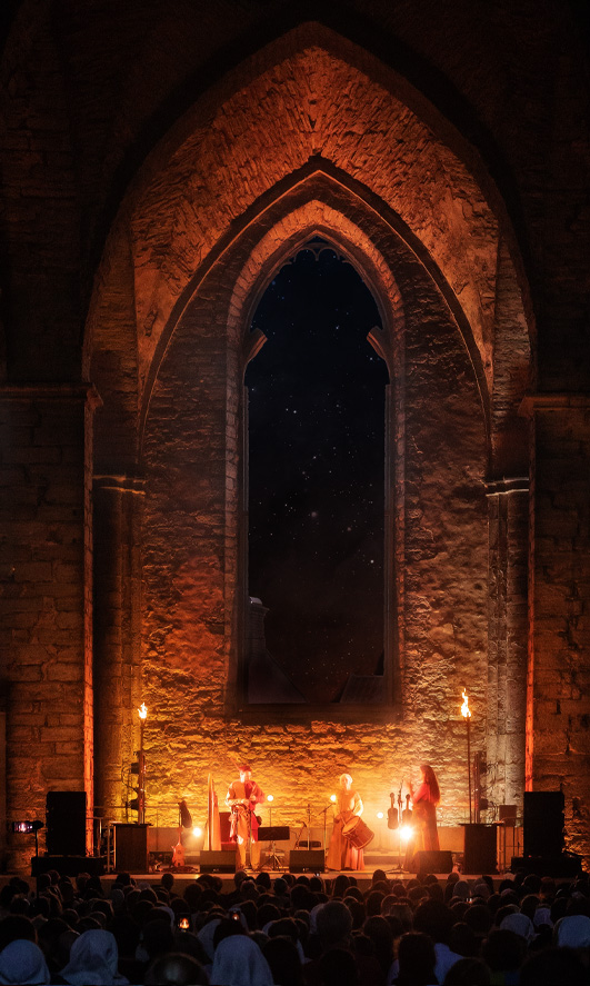 Three musicians on stage in a church ruin